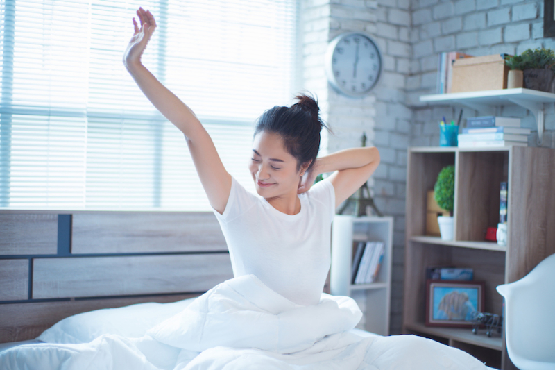 woman waking up in bed, stretching.